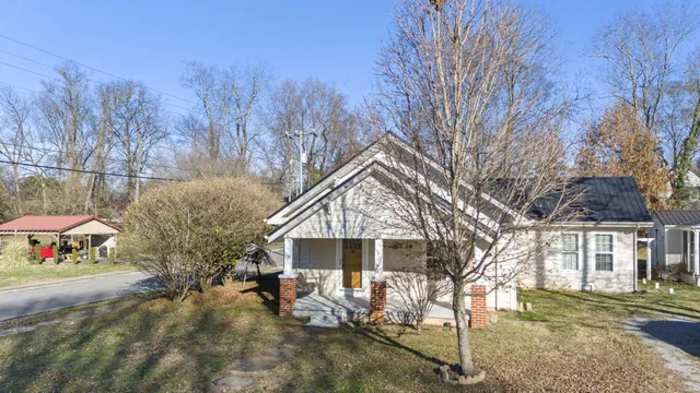 a view of a house with a yard and large tree