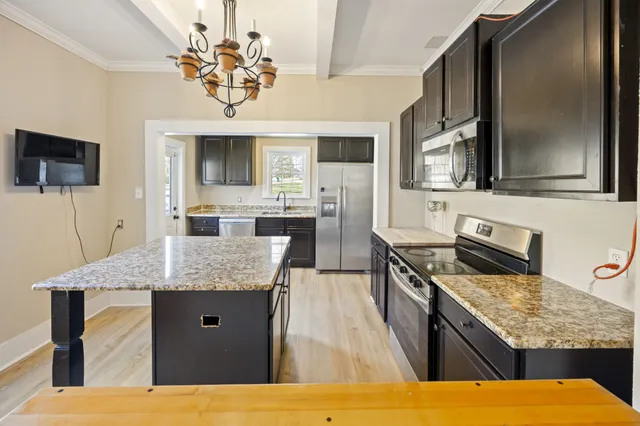 a kitchen with kitchen island granite countertop a sink stove and refrigerator