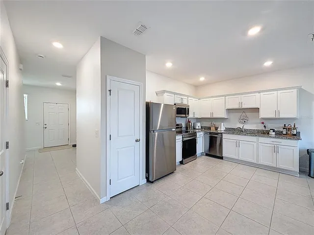 a large kitchen with a refrigerator and white cabinets
