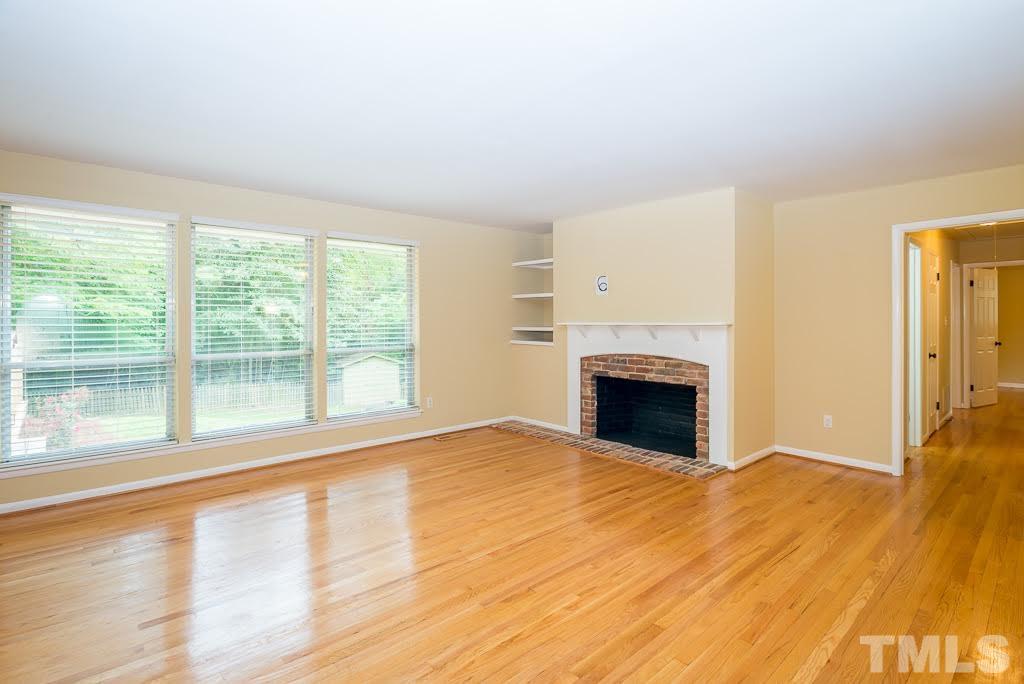 4220 Rowan Street Raleigh, NC 27609 - Photo 8 of 24 a view of empty room with wooden floor and fireplace