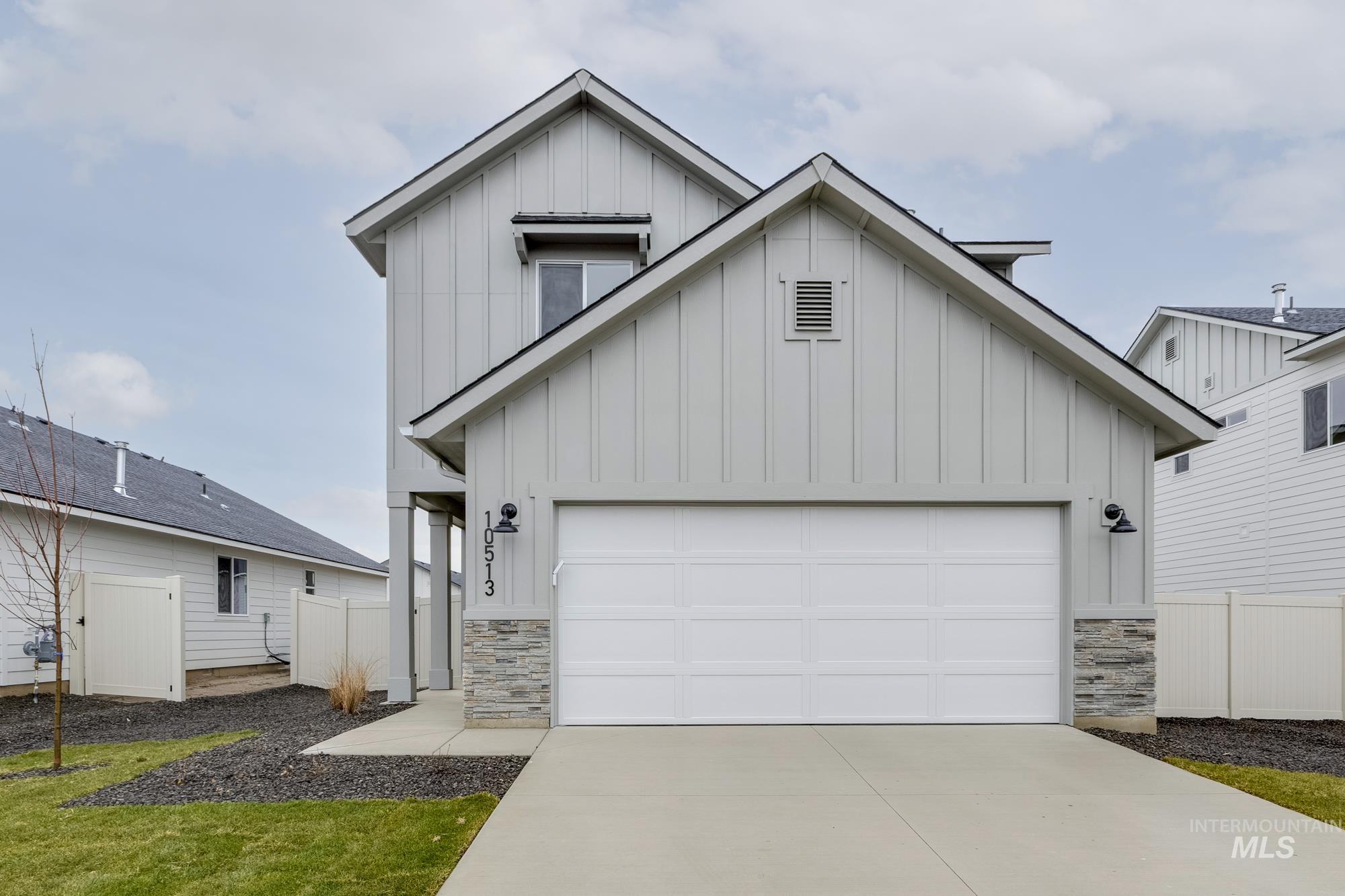 Modern farmhouse featuring board and batten siding, stone siding, and concrete driveway
