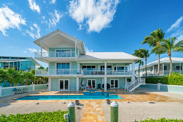 a view of a house with swimming pool lawn chairs and a yard