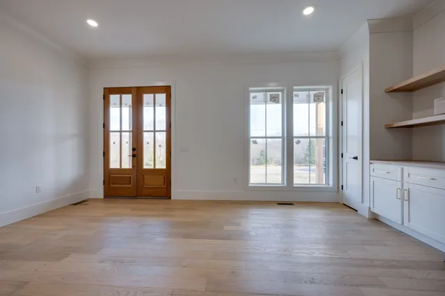 an empty room with wooden floor and windows