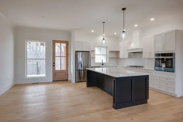 a large kitchen with stainless steel appliances granite countertop a large counter top a stove a refrigerator and a sink