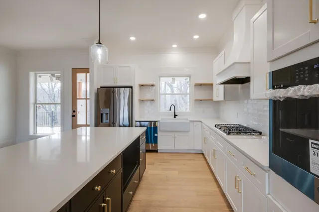 a large kitchen with granite countertop a sink a counter space stainless steel appliances and cabinets