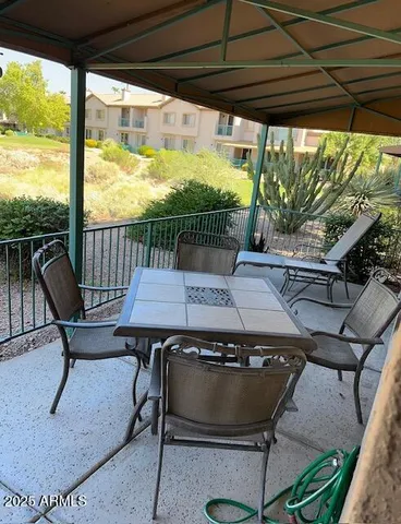 a view of a patio with table and chairs under an umbrella with a small swimming pool