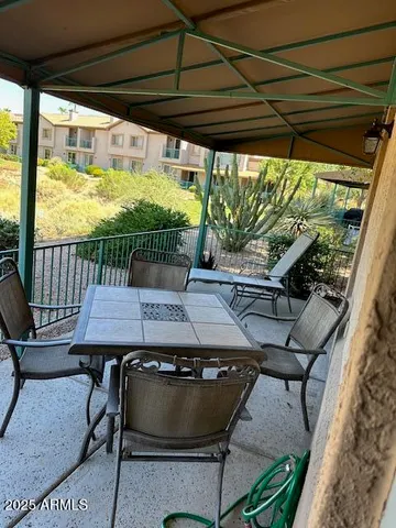 a view of a patio with table and chairs under an umbrella with a small yard