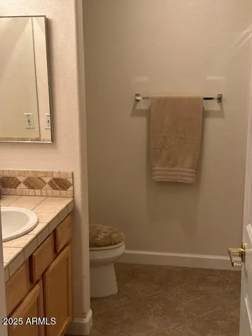 a bathroom with a granite countertop sink and a toilet