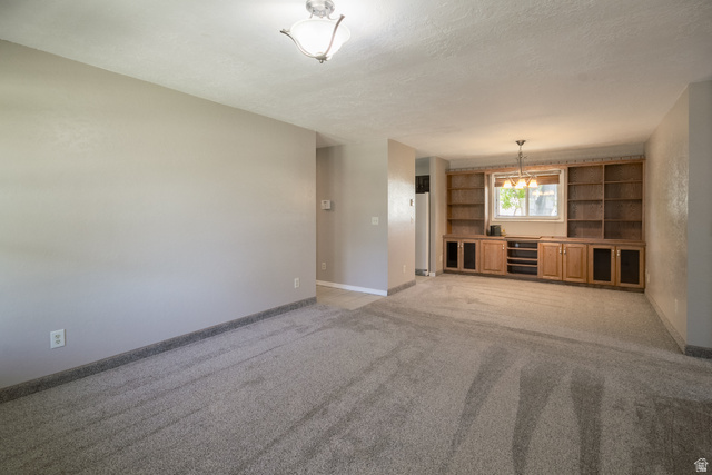 634 South 2100th Street West Vernal, UT 84078 - Photo 5 of 71 Built-in oak shelving and cabinetry with central window, overhead chandelier, and light gray carpet flooring