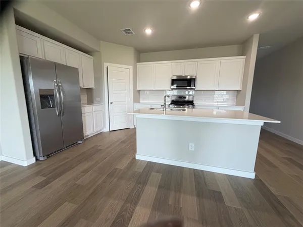 a kitchen with stainless steel appliances a refrigerator a sink a stove and cabinets