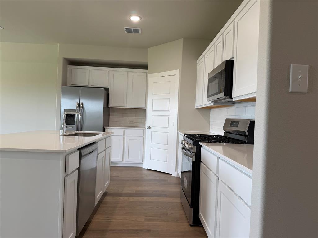 517 River Rdg Drive McKinney, TX 75071 - Photo 4 of 14 a kitchen with stainless steel appliances granite countertop a stove top oven a sink and dishwasher a refrigerator with wooden floor