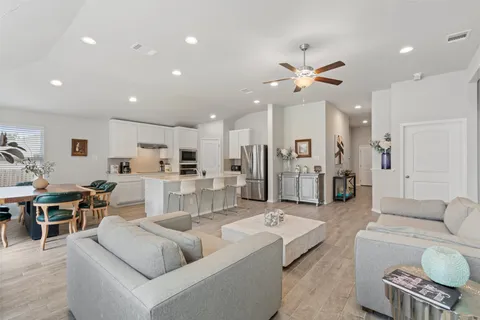 a living room with furniture kitchen view and a chandelier