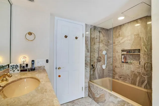 a bathroom with a granite countertop tub sink shower and mirror