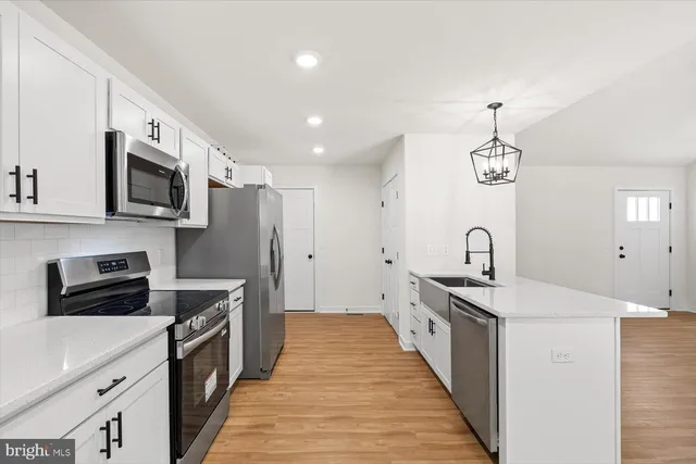 a kitchen with stainless steel appliances granite countertop a sink a stove and a refrigerator