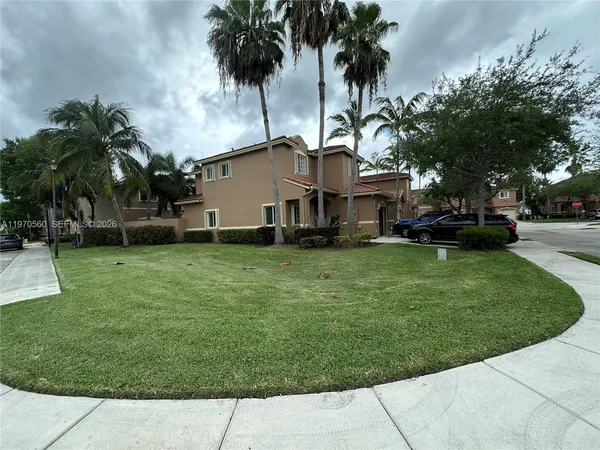 a front view of a house with a garden and trees