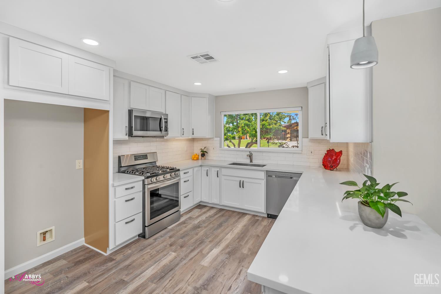 Undisclosed Address Bakersfield, CA 93309 - Photo 7 of 22 a white kitchen with wooden floors stainless steel appliances and a window