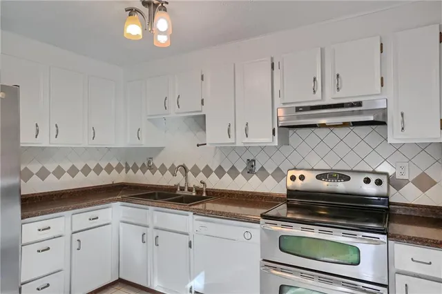 a kitchen with white cabinets and appliances
