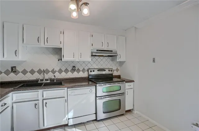 a kitchen with white cabinets and appliances