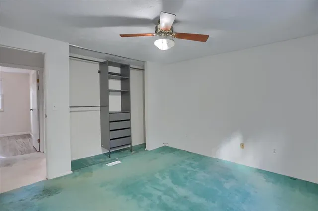 an empty room with closet and ceiling fan