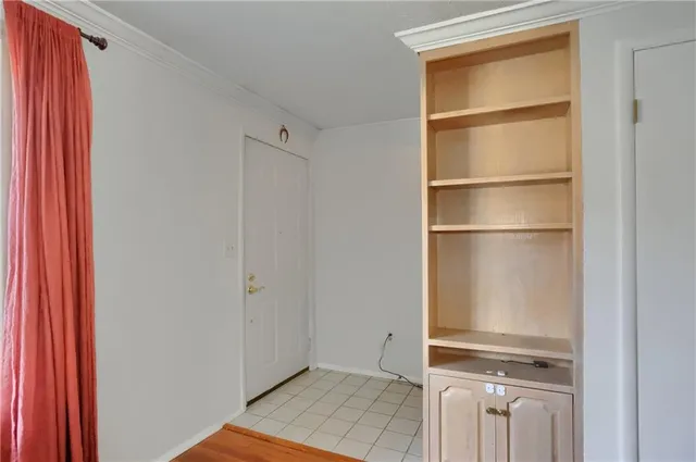 a view of an empty room with cabinet and a window