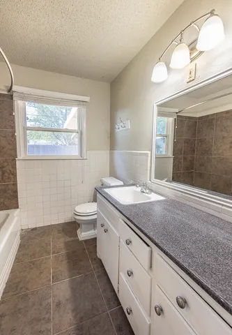 a bathroom with a granite countertop sink a toilet a mirror and shower