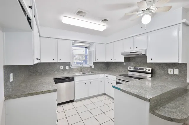 a kitchen with granite countertop white cabinets white appliances a sink and dishwasher