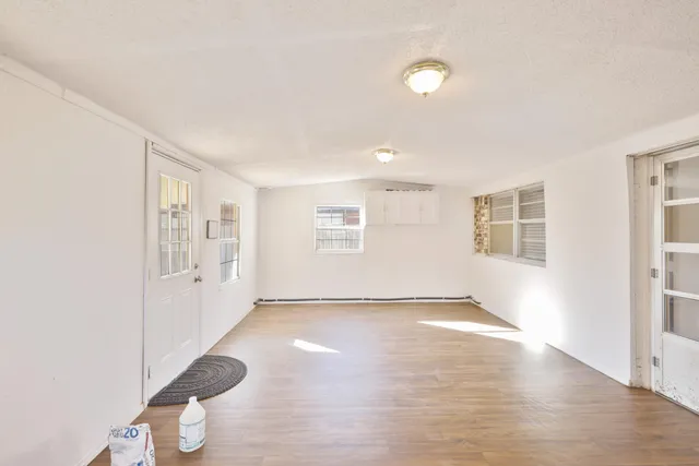 a view of an empty room with a window and wooden floor