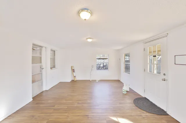 a view of an empty room with window and wooden floor