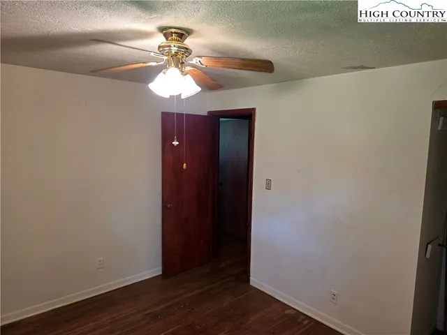an empty room with wooden floor and fan