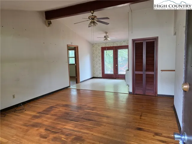 an empty room with wooden floor and a ceiling fan