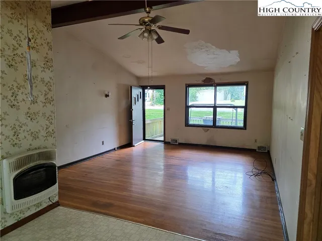 a view of an empty room with a window and wooden floor