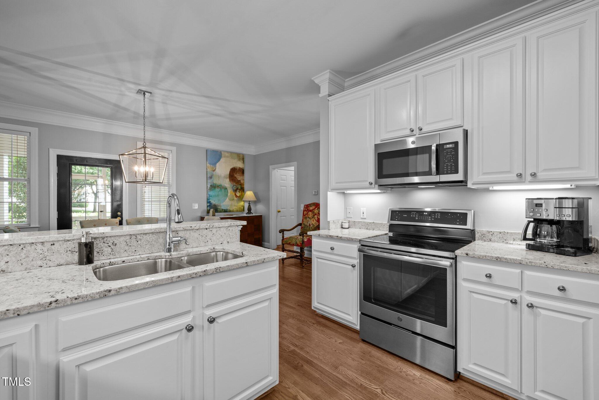 3902 Stags Leap Circle Raleigh, NC 27612 - Photo 15 of 53 a kitchen with stainless steel appliances granite countertop white cabinets a sink a stove a microwave and wooden floors