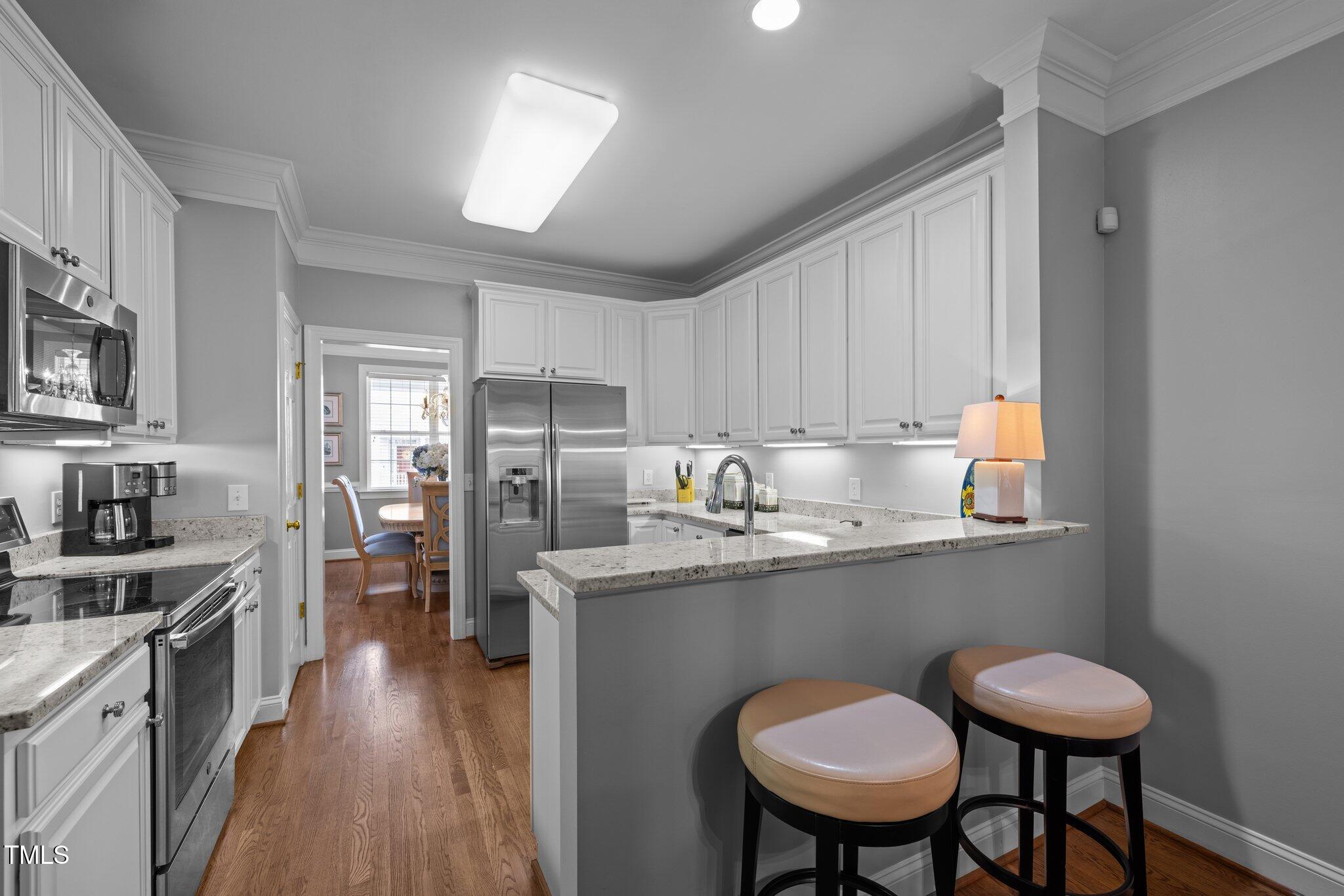 3902 Stags Leap Circle Raleigh, NC 27612 - Photo 16 of 53 a kitchen with stainless steel appliances a dining table chairs sink and cabinets