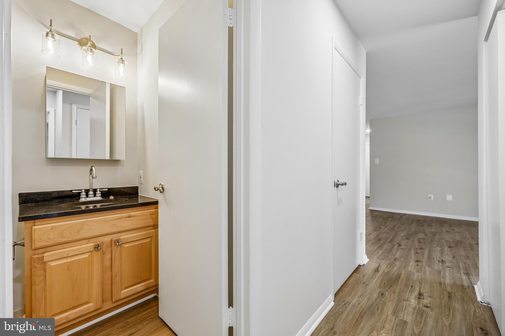 7804 Guildberry Court, Unit 301 Gaithersburg, MD 20879 - Photo 25 of 33 a kitchen with granite countertop a sink a stove and wooden floor