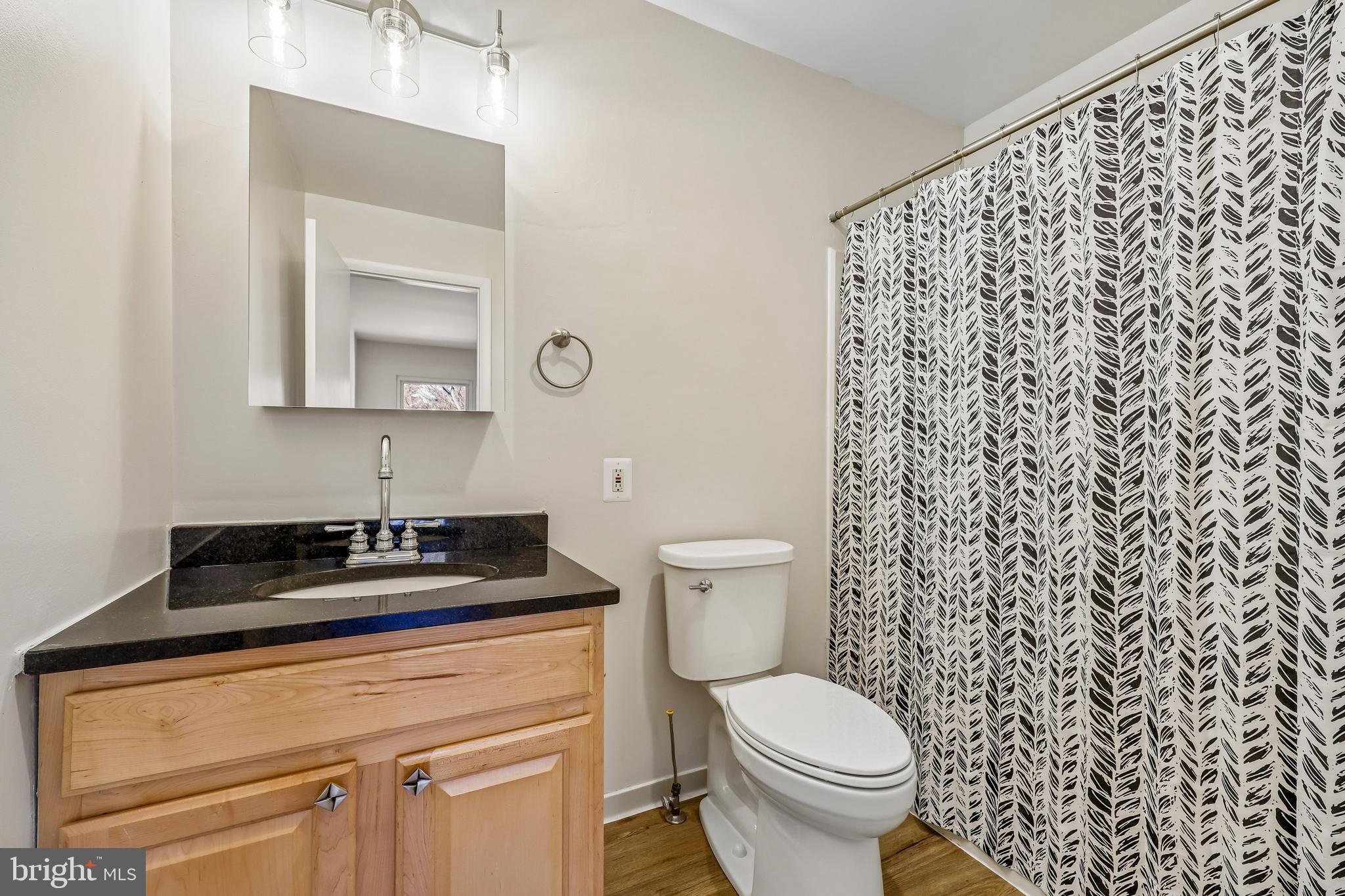 7804 Guildberry Court, Unit 301 Gaithersburg, MD 20879 - Photo 31 of 33 a bathroom with a granite countertop toilet a sink and a mirror