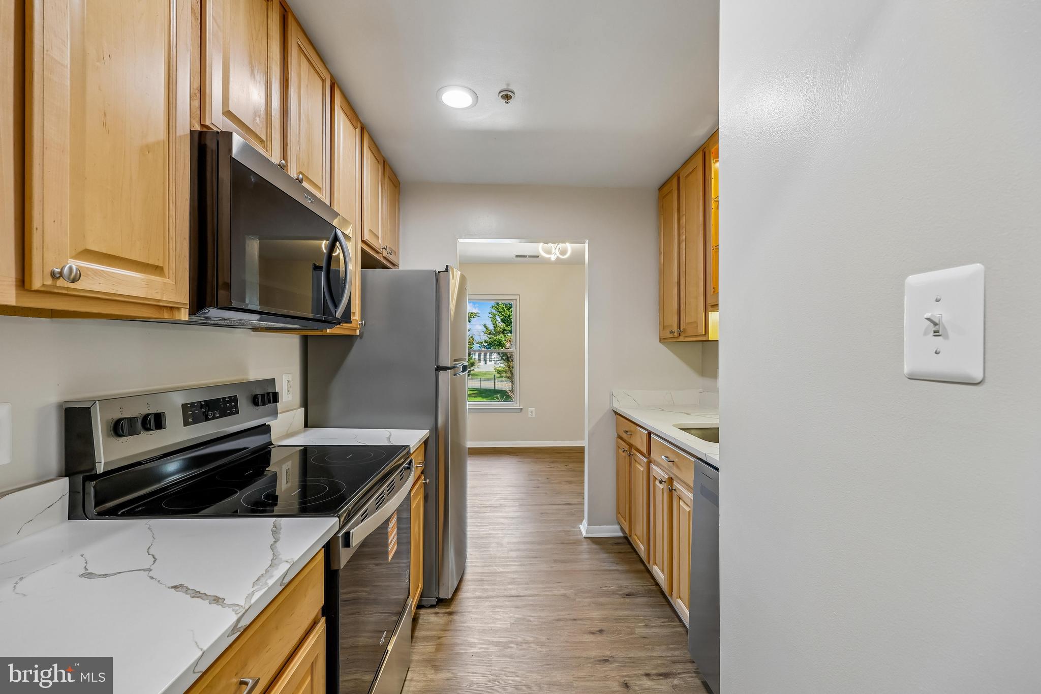 7804 Guildberry Court, Unit 301 Gaithersburg, MD 20879 - Photo 8 of 33 a kitchen with stainless steel appliances a stove a sink a microwave oven a refrigerator white cabinets and wooden floor