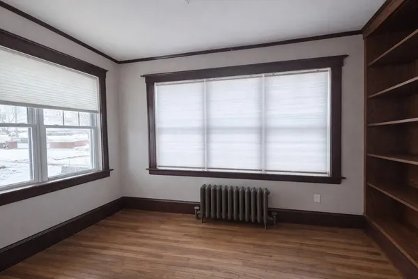 a view of an empty room with wooden floor and a window