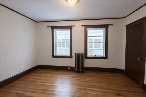 a view of an empty room with window and wooden floor