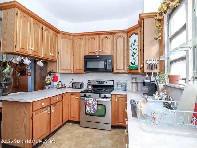 a kitchen with stainless steel appliances granite countertop a stove top oven a sink dishwasher and a microwave oven with large wooden cabinets