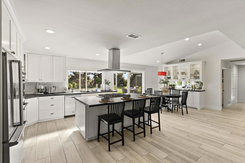 147 Witham Road Encinitas, CA 92024 - Photo 15 of 47 a kitchen with stainless steel appliances kitchen island granite countertop a table chairs sink and cabinets