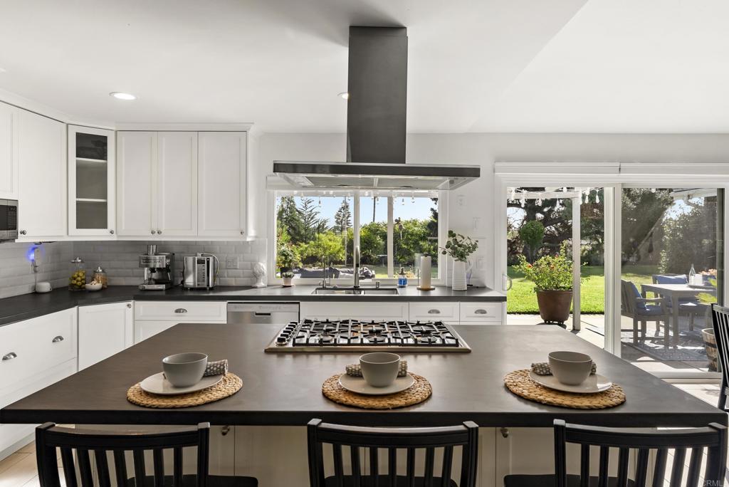 147 Witham Road Encinitas, CA 92024 - Photo 16 of 47 a table with a stove and white kitchen island with wooden floor