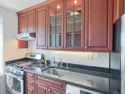 a kitchen with granite countertop a sink stove and cabinets