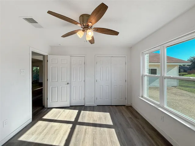 a view of an empty room with a window and wooden floor