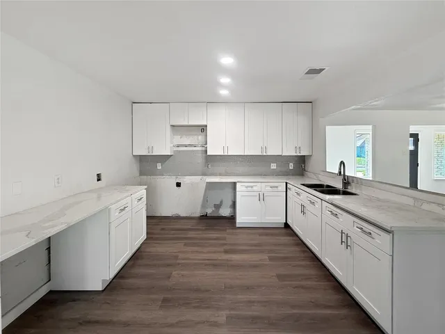 a large kitchen with cabinets stainless steel appliances a sink and a window