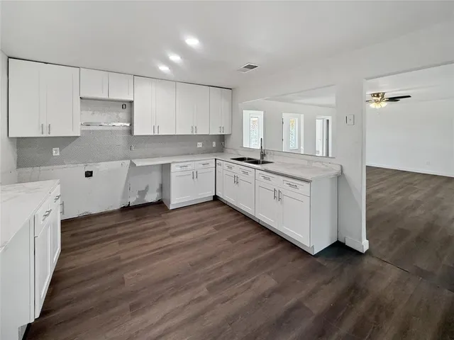 a room with kitchen island granite countertop wooden floors and white cabinets