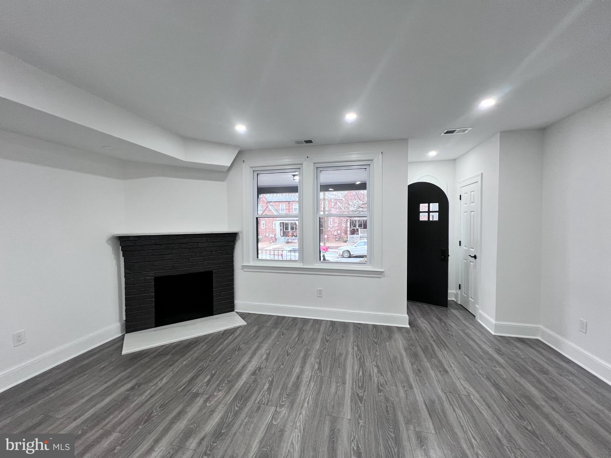 216 Jefferson Street Northwest, Unit A Washington, DC 20011 - Photo 2 of 32 an empty room with wooden floor and fireplace