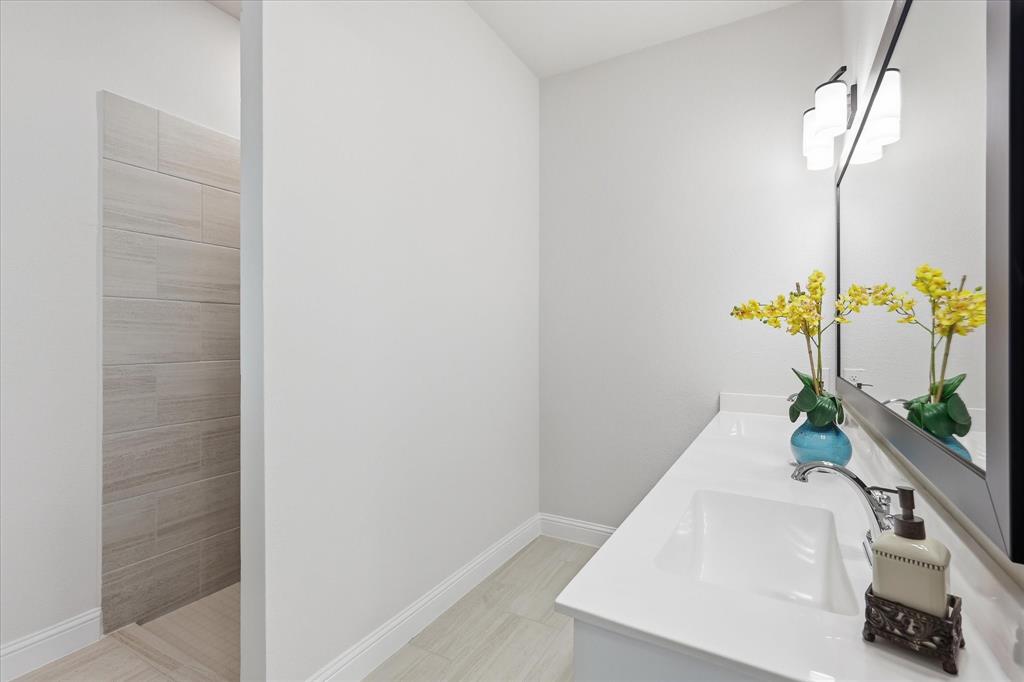 4017 Alpine Street Midlothian, TX 76065 - Photo 20 of 37 Bathroom featuring a single vanity with an integrated sink, polished chrome faucet, and expansive wall-mounted mirror with a black frame