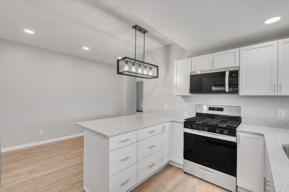 8850 Ridgewood Road Rock Island, IL 61201 - Photo 12 of 45 a kitchen with stainless steel appliances a white stove top oven a sink dishwasher and white cabinets with wooden floor