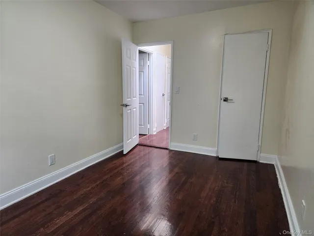 a view of an empty room with wooden floor and closet