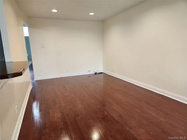 an empty room with wooden floor and mirror